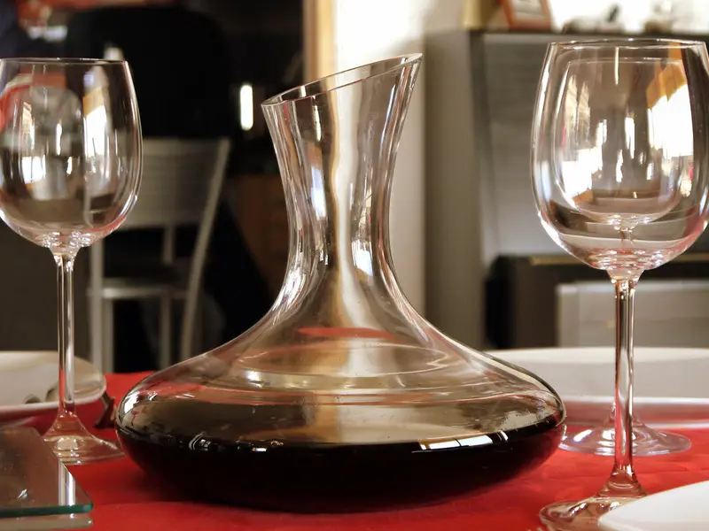 Mesa con mantel rojo, copas y un decantador de vino